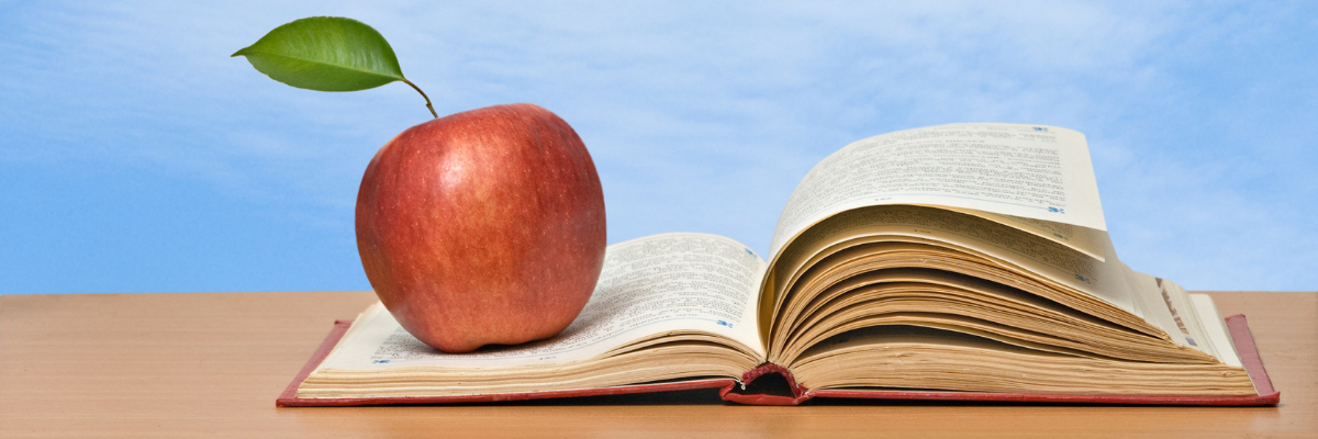 open book with red apple on top