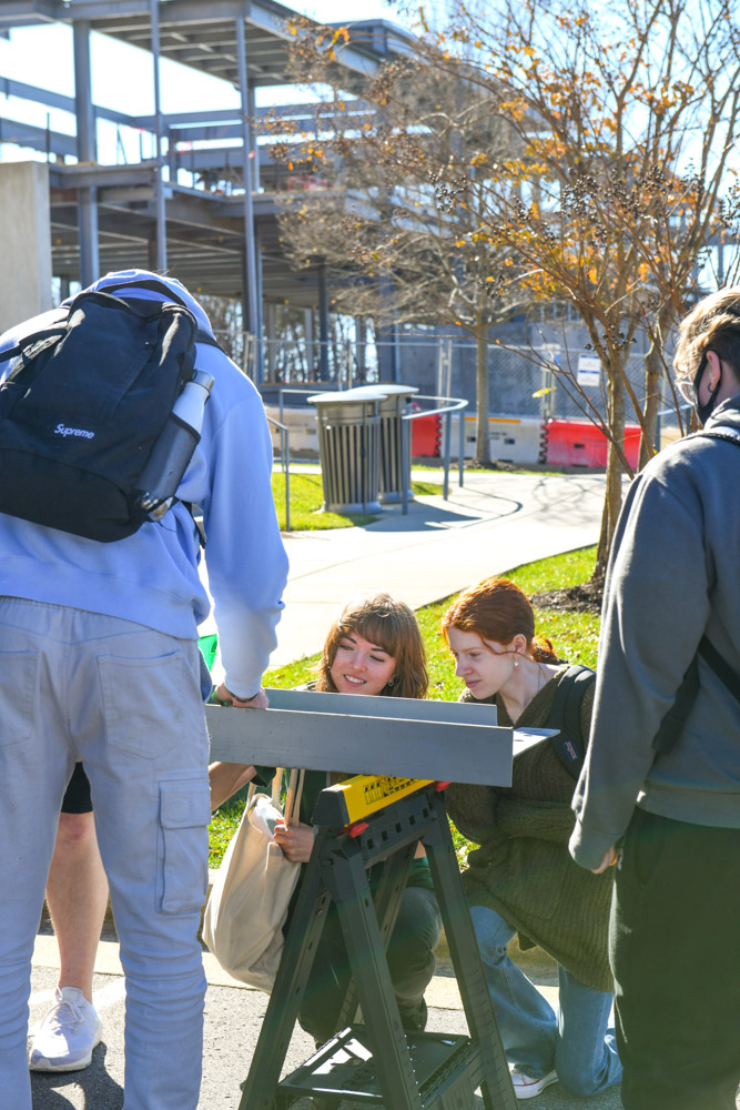 Students add their signatures to a beam that will be inserted in the new Arts and Technology Building—which can be seen under construction in the background—on Columbia State Community College’s Williamson Campus.