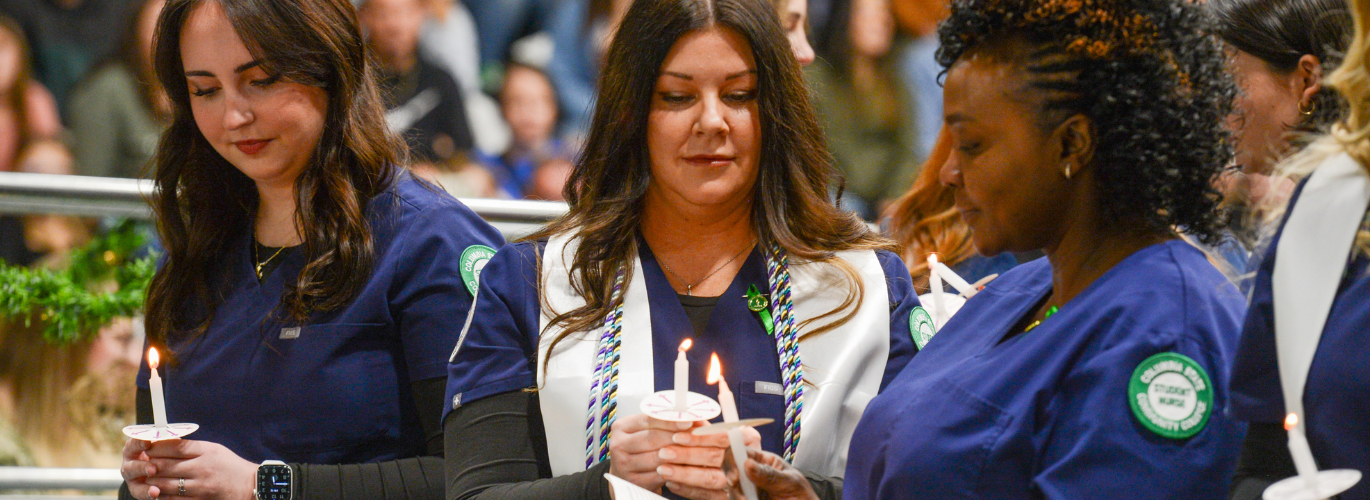 Fall 2025 Columbia State nursing graduates light each others candles at the pinning ceremony.