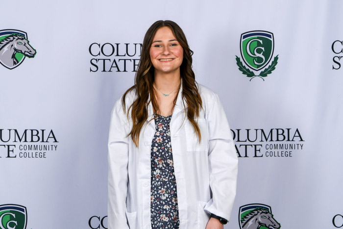 A person stands in front of a white background. 