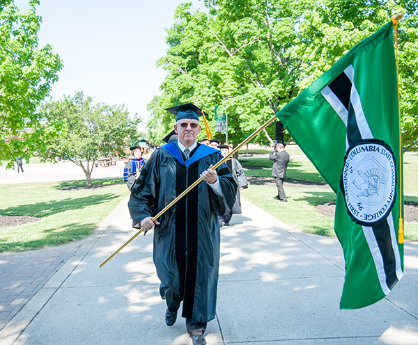 Glenn Hudson carries the College flag at Commencement