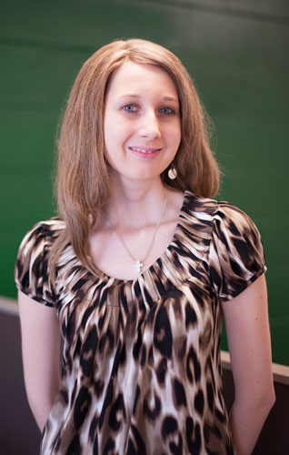 Young woman standing by green wall